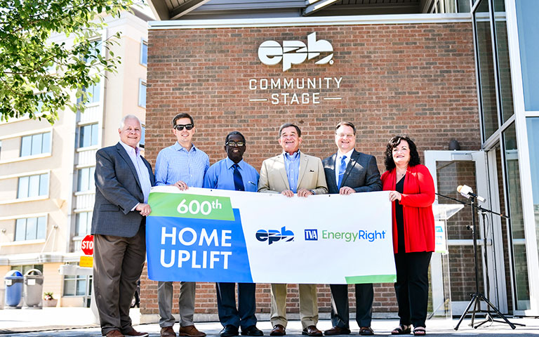 EPB employees on a stage with a 600th Home Uplift banner