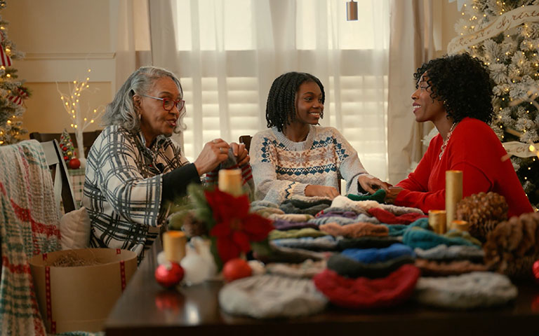 Family gathered around a dining table making hats at Christmas time