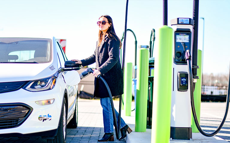 Woman charging an electric car at a charging station